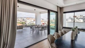 Une chambre d’hôtel moderne dotée d’une grande fenêtre, d’un coin repas avec des chaises et une table, et offrant une vue sur le paysage urbain.