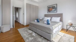 Une chambre à coucher moderne avec un lit, des tables de chevet et un tableau accroché au mur.