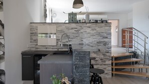 Eine moderne Küche mit Steinrückwand, einer eingebauten Spüle und einer kleinen Essecke mit Tisch und Stühlen.