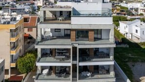 Un edificio residencial de varios pisos con balcones, ventanas grandes y techo plano.