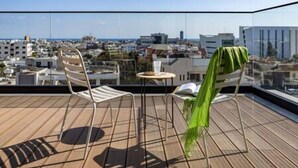 Una terrazza sul tetto con vista sulla città, una sedia e un tavolino.