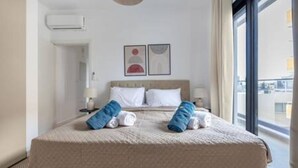 Una camera d'albergo con un letto, una finestra e un condizionatore d'aria a parete.