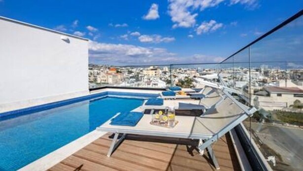 Una piscina sul tetto con lettini e un tavolo, con vista sulla città.