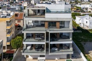 Un edificio residencial de varios pisos con balcones, ventanas grandes y techo plano.