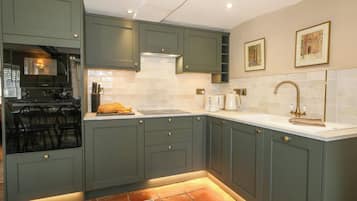 A kitchen with dark cabinets, a stove, a sink, and a tiled backsplash.
