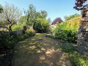 Ein Garten mit Steinmauer, Holzfence und unterschiedlichen Pflanzen.