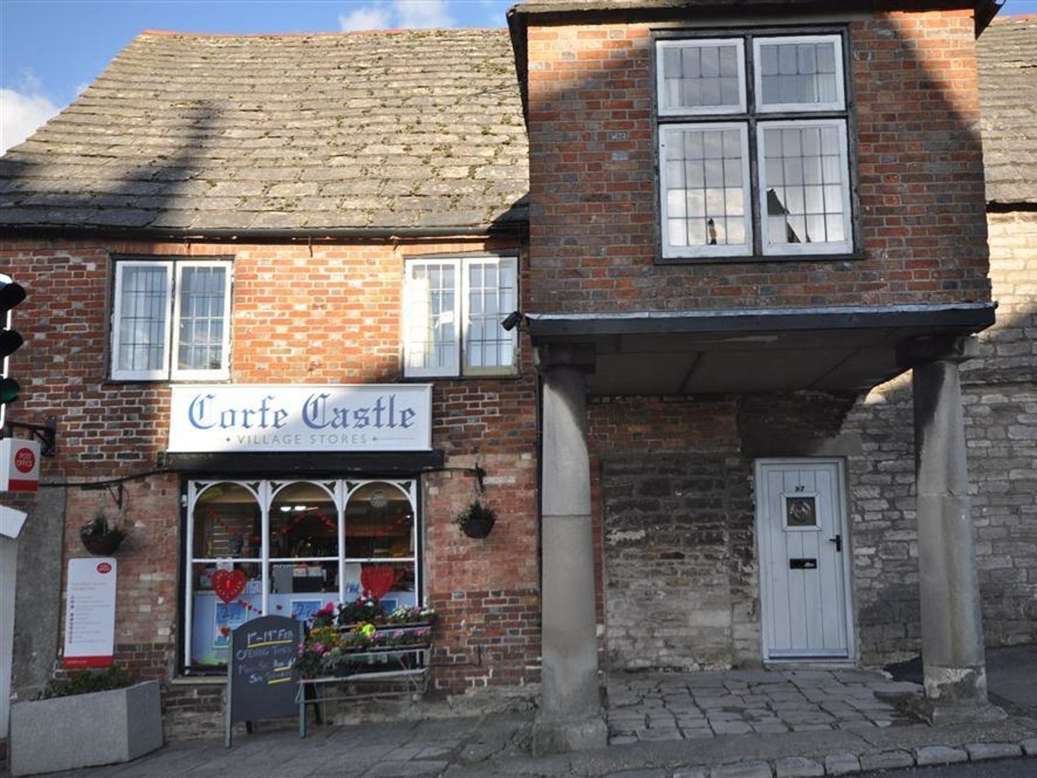 A brick building with a sign reading 'Corfe Castle Village Stores.'