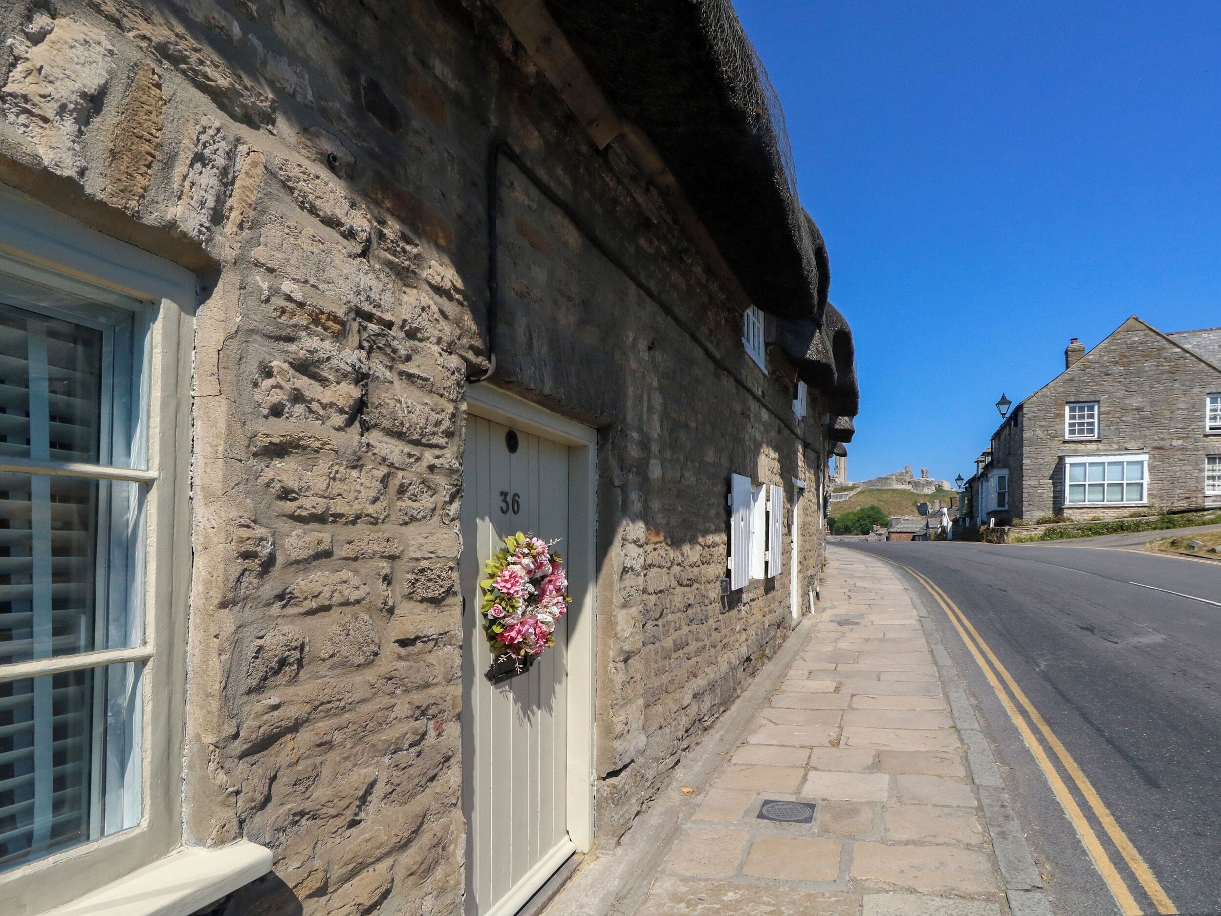 A stone building with a white door marked '36' and a flower arrangement on the door.