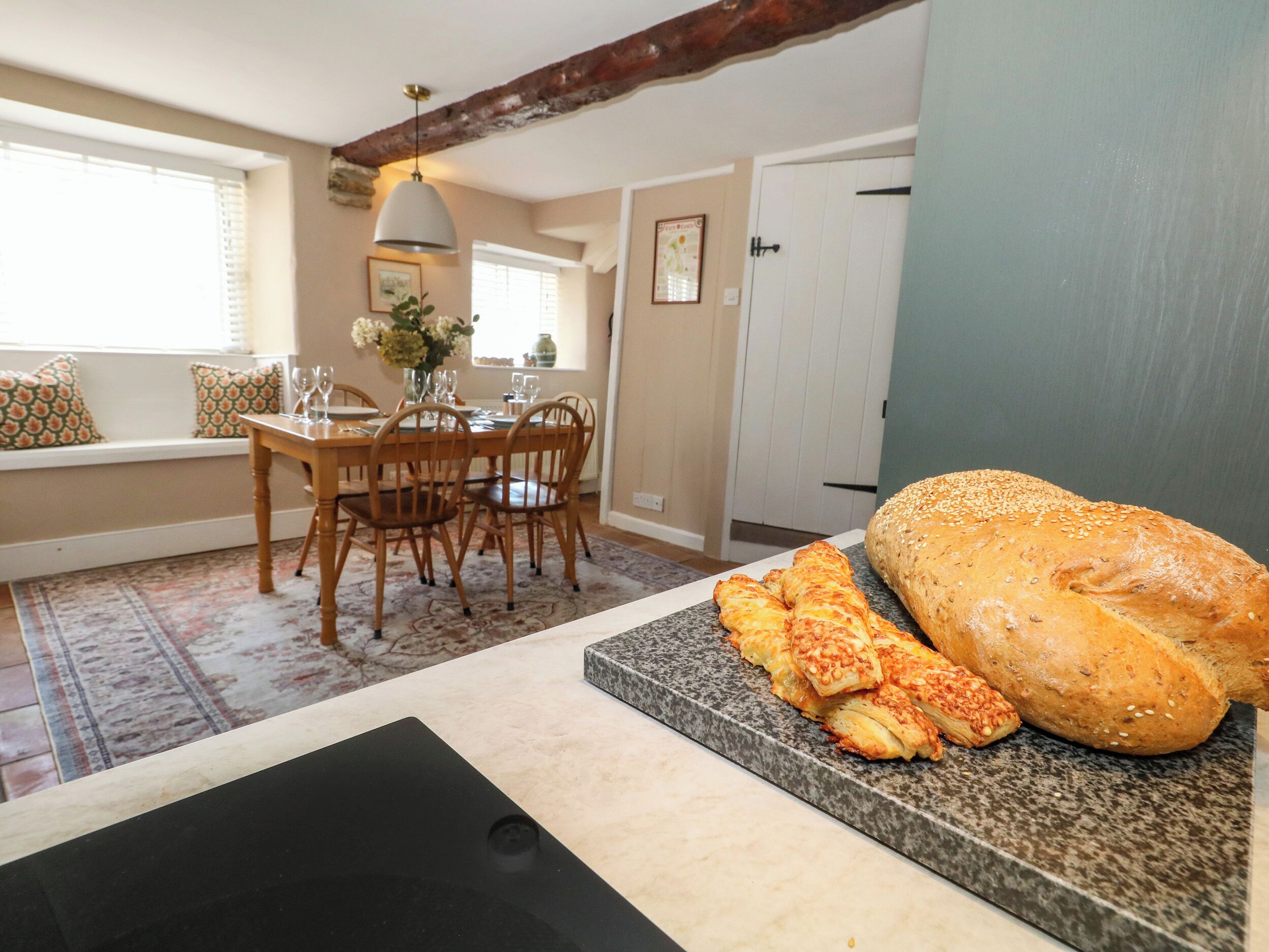 Une cuisine avec un coin repas, une grande miche de pain et une planche à découper avec des tranches de pain.