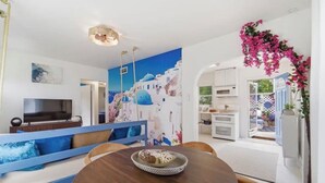 A modern living room with a blue sofa, a round wooden table, and a TV.