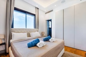 A modern hotel room with a large bed, a wardrobe, and a window with curtains. - 301 Piliou - Large Terrace & Rooftop Communal Pool (Limassol)