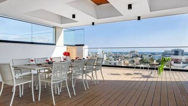 Une terrasse sur le toit, avec une table et des chaises pour prendre les repas, une vue sur le paysage urbain et une plateforme en bois.