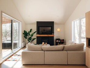 Ein modernes Wohnzimmer mit einer großen Couch, einem Kamin und einem Fernseher.