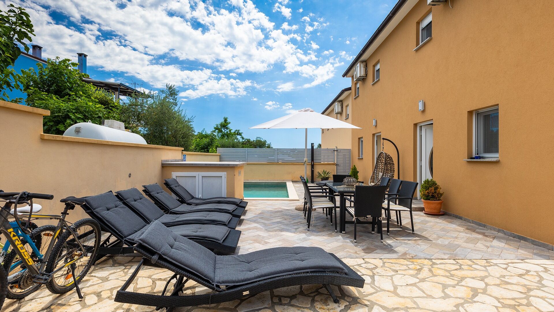 A patio with outdoor seating, a pool, and a bicycle.