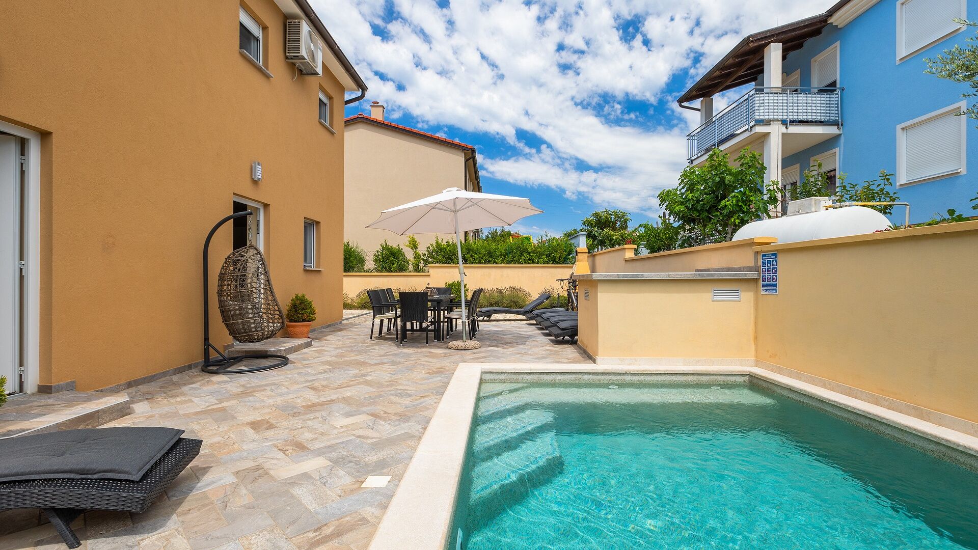A pool area with a lounge chair, a table, and an umbrella.