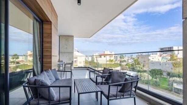 Ein Balkon mit Gartenmöbeln, Blick auf die Stadt und einem wolkenlosen Himmel.