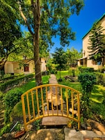 Un sendero conduce a un edificio con una puerta metálica curva, rodeado de abundante vegetación y árboles.