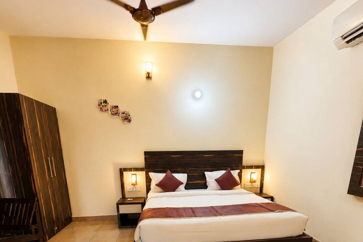 A bedroom with a bed, a ceiling fan, a nightstand, a wardrobe, and a wall-mounted air conditioner.