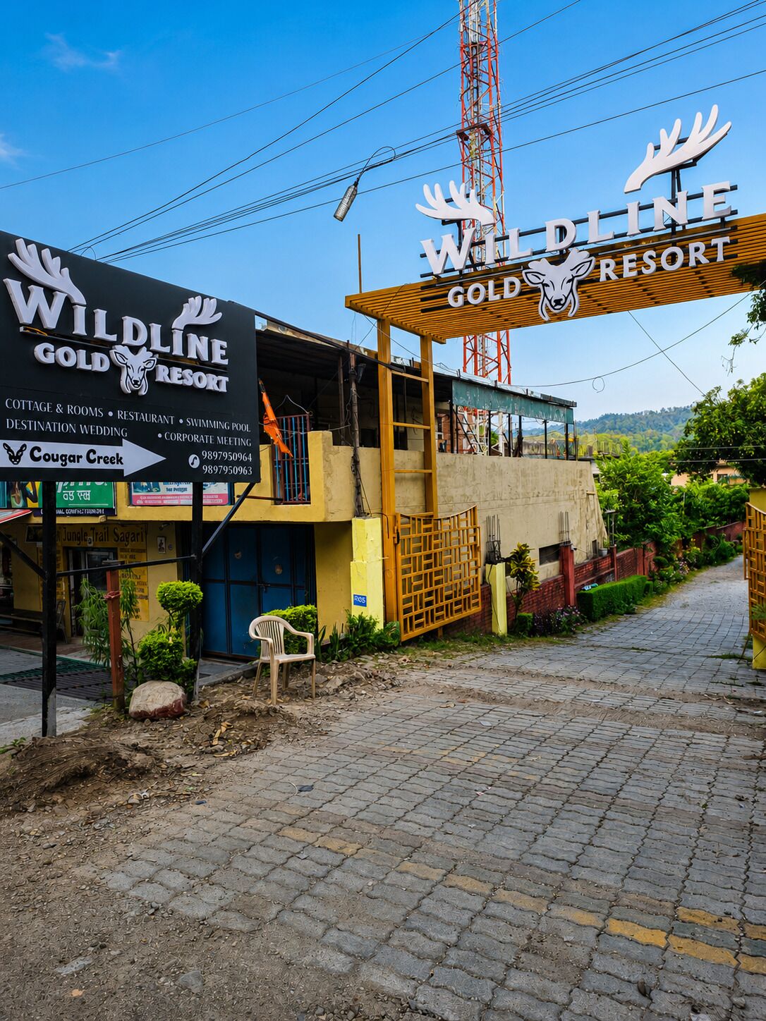 A building with a sign for Wildline Gold Resort, indicating it offers cottages, rooms, a restaurant, a swimming pool, and a destination wedding.