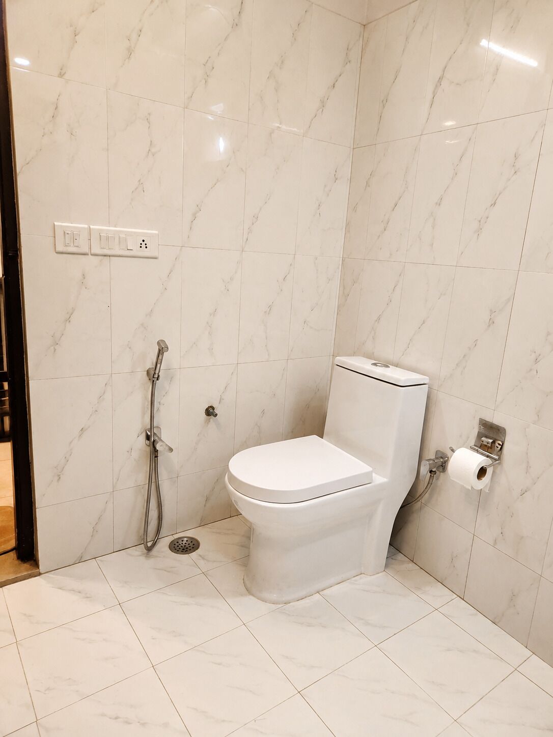 A bathroom with a toilet, a shower, and a toilet paper holder.