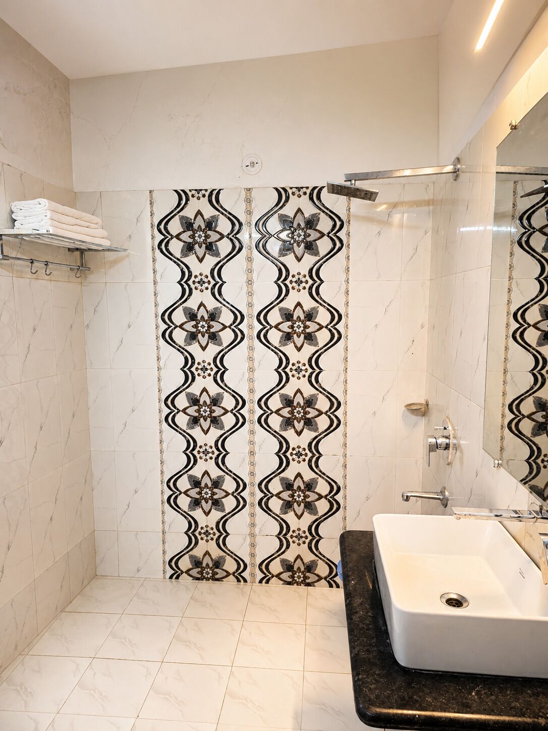 A bathroom with a shower, a sink, and a towel rack.