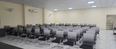 A room with rows of black and white chairs, a marble floor, and a ceiling with fluorescent lights.