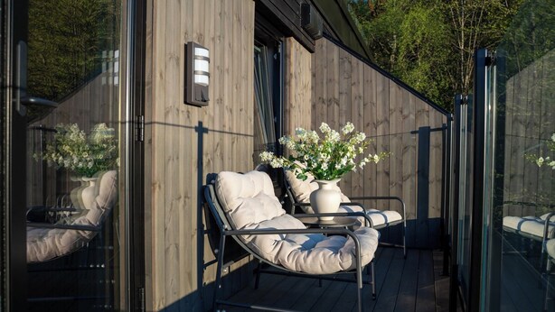 Een moderne zithoek buiten, met comfortabele fauteuils en een bloemenvaas.