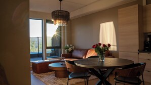 Een moderne eetruimte met een ronde tafel, stoelen, een bank en een kroonluchter.