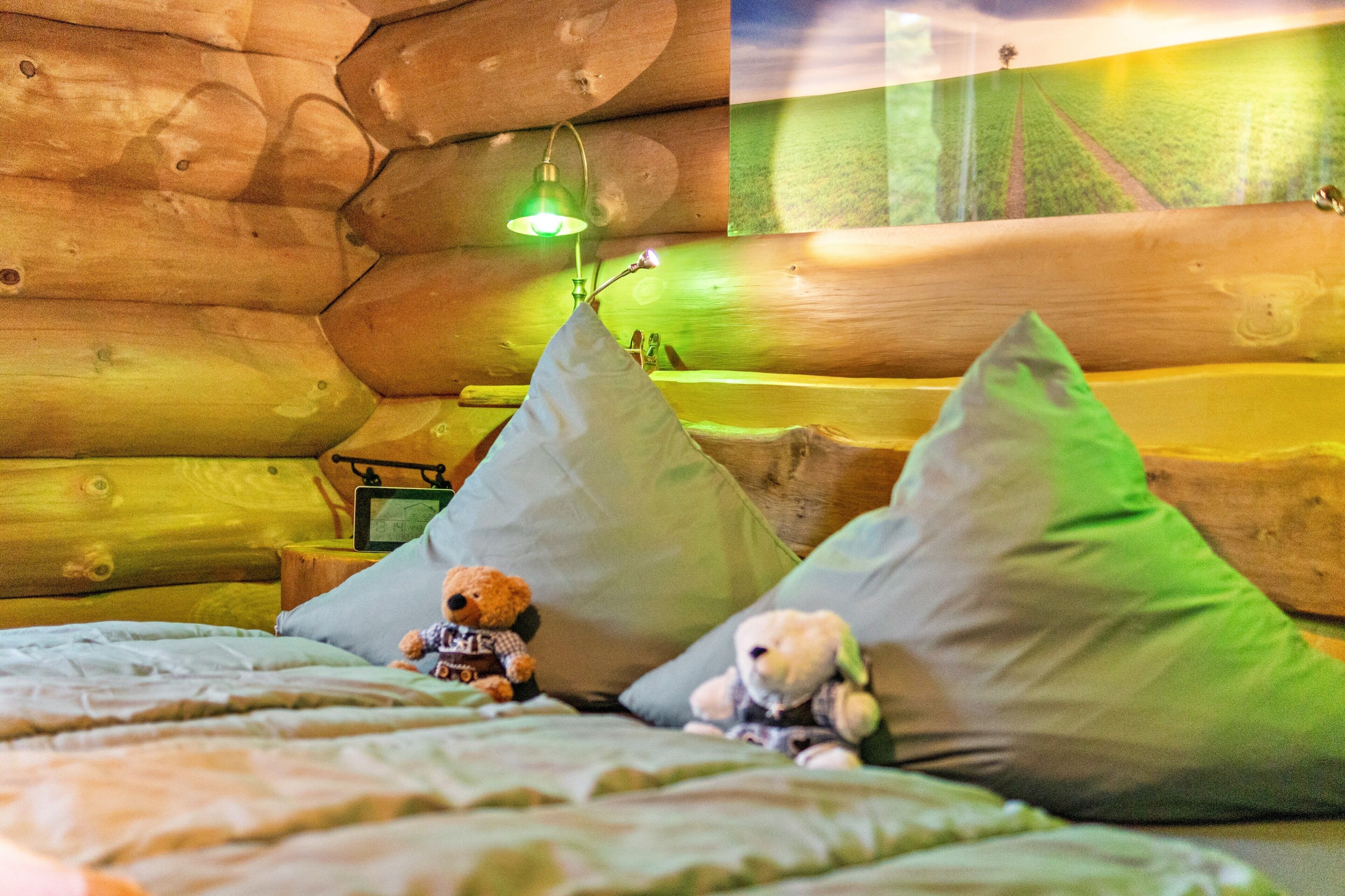 A cozy log cabin room with a bed, pillows, and two teddy bears.
