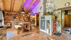 Interior d'una cabana rústica amb parets de fusta, una llar de pedra i zona de dinar.
