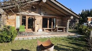 Una cabaña de madera con un patio, una mesa de comedor y una silla.