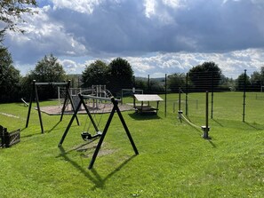 A playground with swings, a climbing structure, and a picnic table. - Attractive detached house with hot tub (Winterberg)