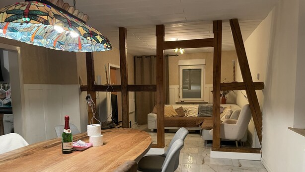 A dining area with a wooden table, chairs, a bottle of champagne, and a stained glass light fixture.
