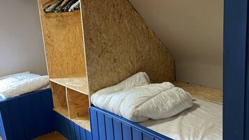 Ein Zimmer mit Etagenbett, Holzböden und schrägem Dach.