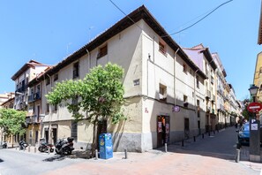 A street with buildings, a tree, and parked motorcycles. - (ESC2225) Study in the Center of Madrid (Madrid)