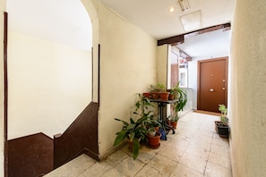 A hallway with a staircase, potted plants, and a door at the end. - (ESC2225) Study in the Center of Madrid (Madrid)