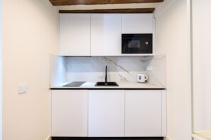 A kitchen with white cabinets, a marble countertop, a built-in oven, and a coffee maker. - (ESC2225) Study in the Center of Madrid (Madrid)