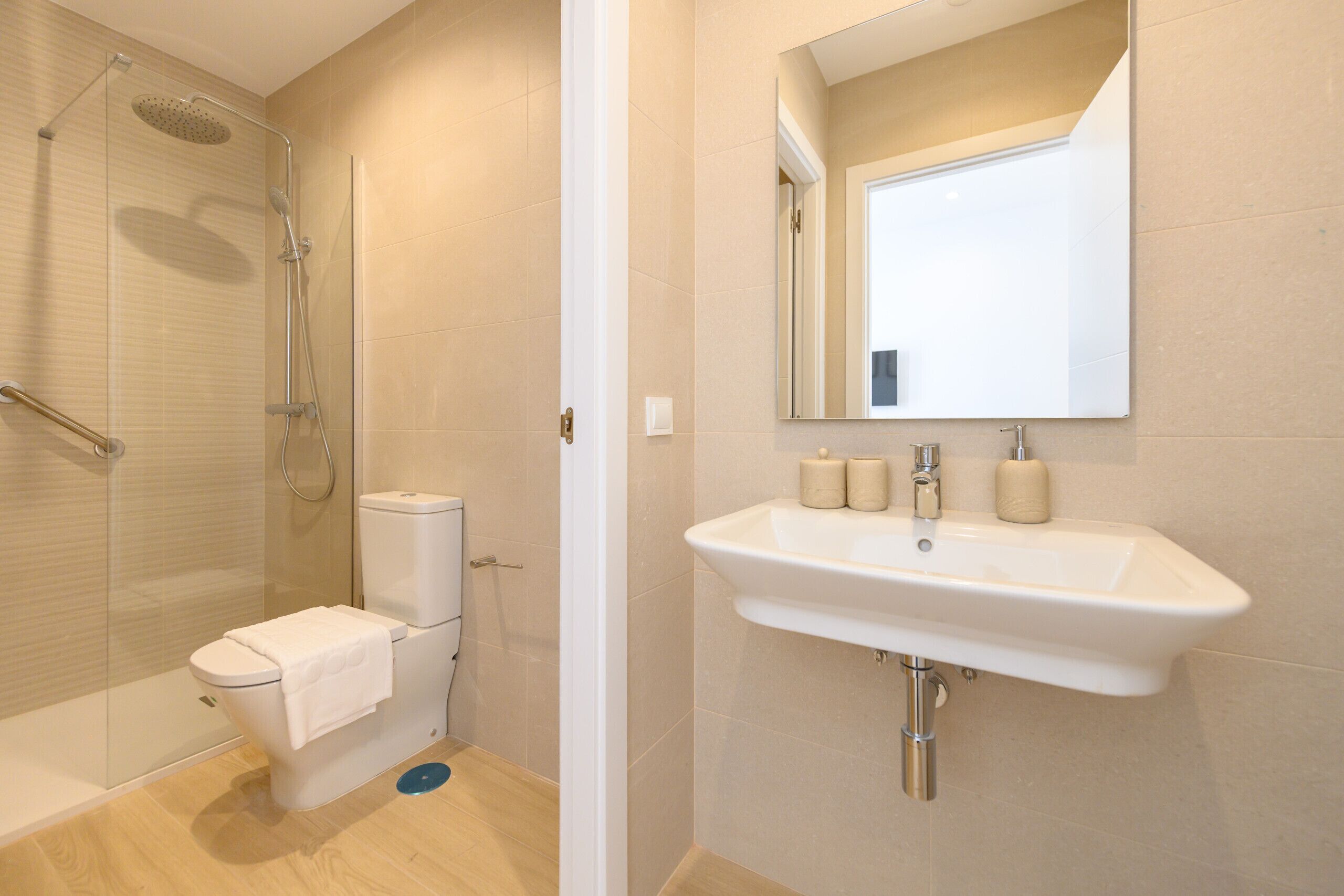 Une salle de bain moderne avec une douche à parois de verre, des toilettes et un lavabo surmonté d’un miroir.
