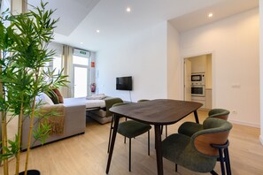 A modern living room with a dining area, a sofa, a television, and a kitchen in the background. - (SDB1L4) 1 bedroom apartment in Tetuán, Madrid (Madrid)