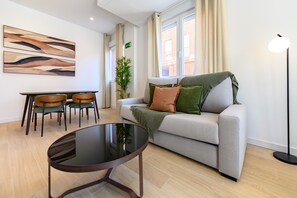 A modern living room with a sofa, a glass coffee table, and a dining area with chairs. - (SDB1L4) 1 bedroom apartment in Tetuán, Madrid (Madrid)