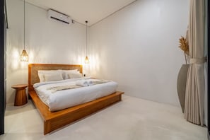 Un dormitorio moderno con una cama de madera, ropa de cama blanca, dos lámparas de noche, un equipo de aire acondicionado y un ventanal con cortinas.