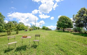 A grassy outdoor area with a wooden bench, a table with a bowl, and a tree. - Gorgeous home in Saturnia (Saturnia)