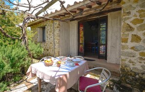 Un edificio de piedra con una mesa dispuesta para una comida, una silla y un pequeño jardín.