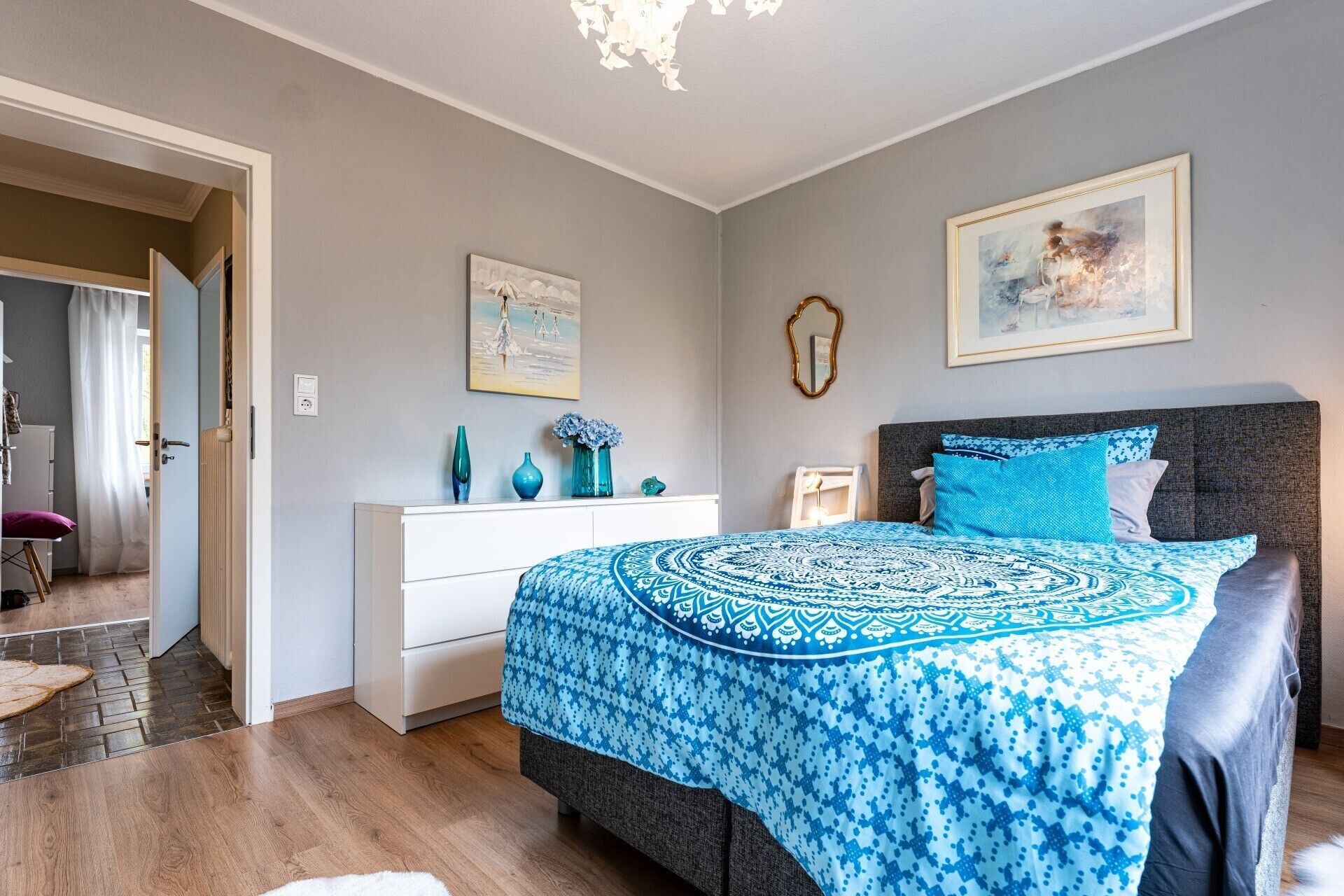 Ein Schlafzimmer mit einem Bett, einem Schminktisch, einem Spiegel und zwei Bildern an der Wand.