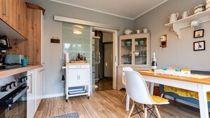 Une cuisine moderne avec des meubles en bois, un coin repas doté d’une table et de chaises blanches, et un meuble encastré avec des portes en verre.