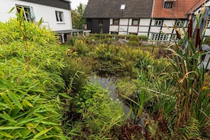 Un quartier résidentiel avec un petit plan d’eau, entouré d’une végétation luxuriante et de maisons à l’architecture traditionnelle.