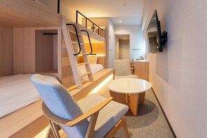 Una habitación de hotel moderna con una cama litera, un escritorio, una silla y una mesa redonda.