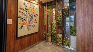 Un corridoio con un'ampia opera d'arte floreale sulla parete, rivestimenti in legno e giardini verticali.