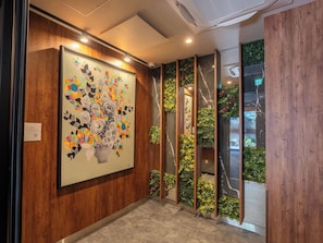 Un couloir orné d’une grande œuvre d’art florale au mur, doté de lambris en bois et de jardins verticaux.