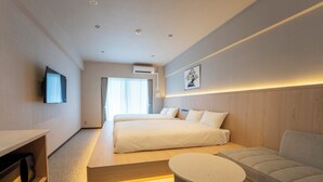 Una camera d'hotel con un letto, un divano, una TV, un comodino e un condizionatore d'aria a parete.